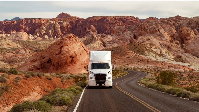 A truck driving towards the camera with a desert mesa in the background