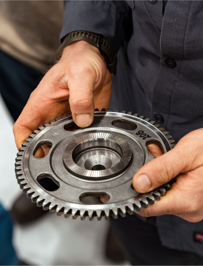 A worker holding a metal cog